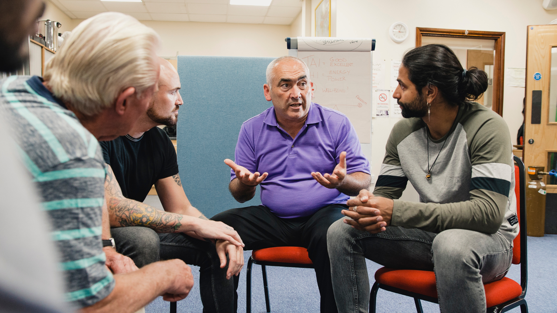 Four men sitting in a circle talking
