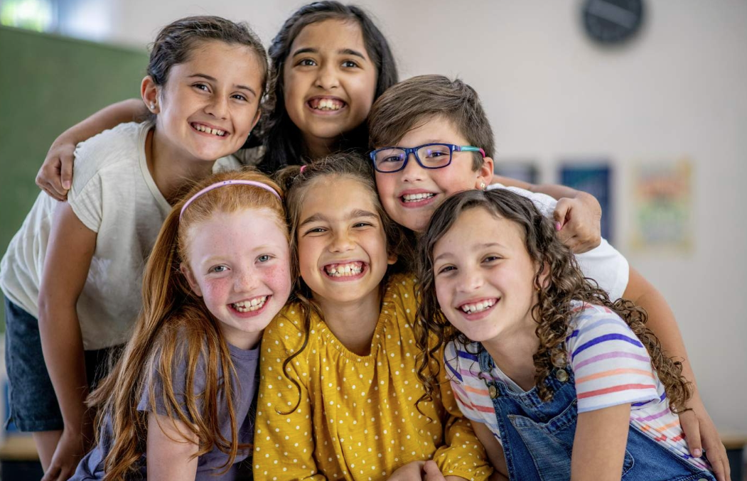 6 small children huddled together smiling