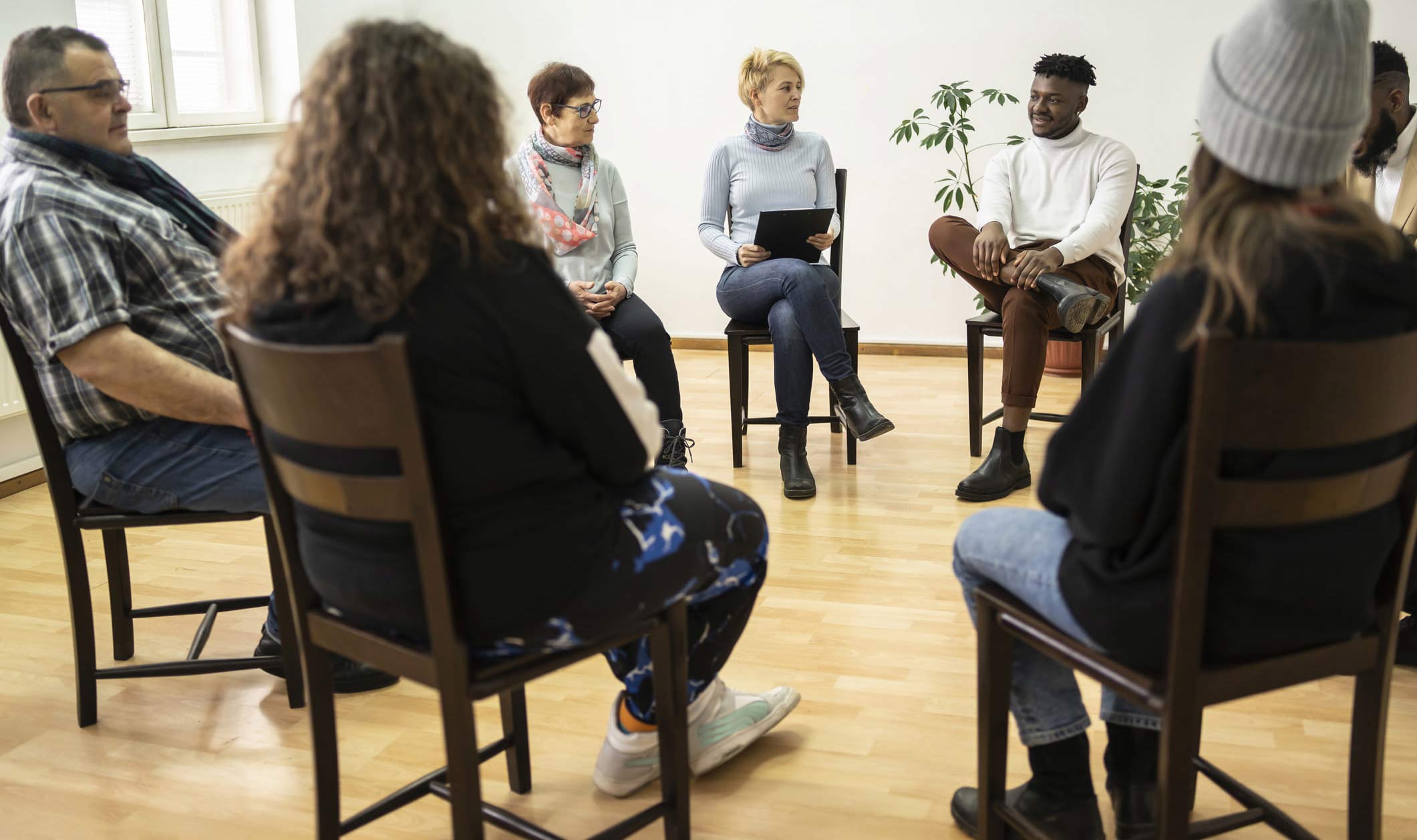 adults sitting on chairs in a circle having a discussion